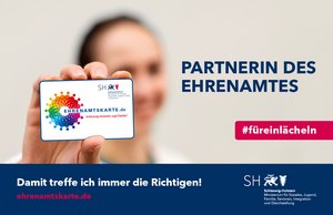 Eine Frau halt eine Ehrenamtskarte in die Kamera.