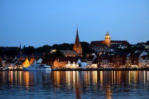 Das Bild zeigt die Stadtansicht von Flensburg vom Wasser aus bei abendlicher Stimmung.