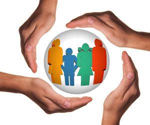 Vier Hände schützen eine Glaskugel in der stilisiert eine vierköpfige Familie in bunten Farben zu sehen ist.