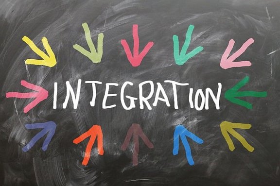 vor dunklem Hintergrund steht in weißen Druckbuchstaben das Wort Integration; bunte Pfeile zeigen im Kreis um das Wort herum angeordnet auf den Begriff.