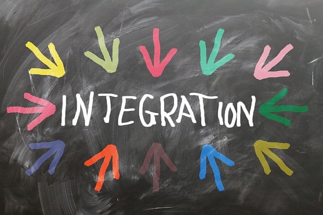 vor dunklem Hintergrund steht in weißen Druckbuchstaben das Wort Integration; bunte Pfeile zeigen im Kreis um das Wort herum angeordnet auf den Begriff.