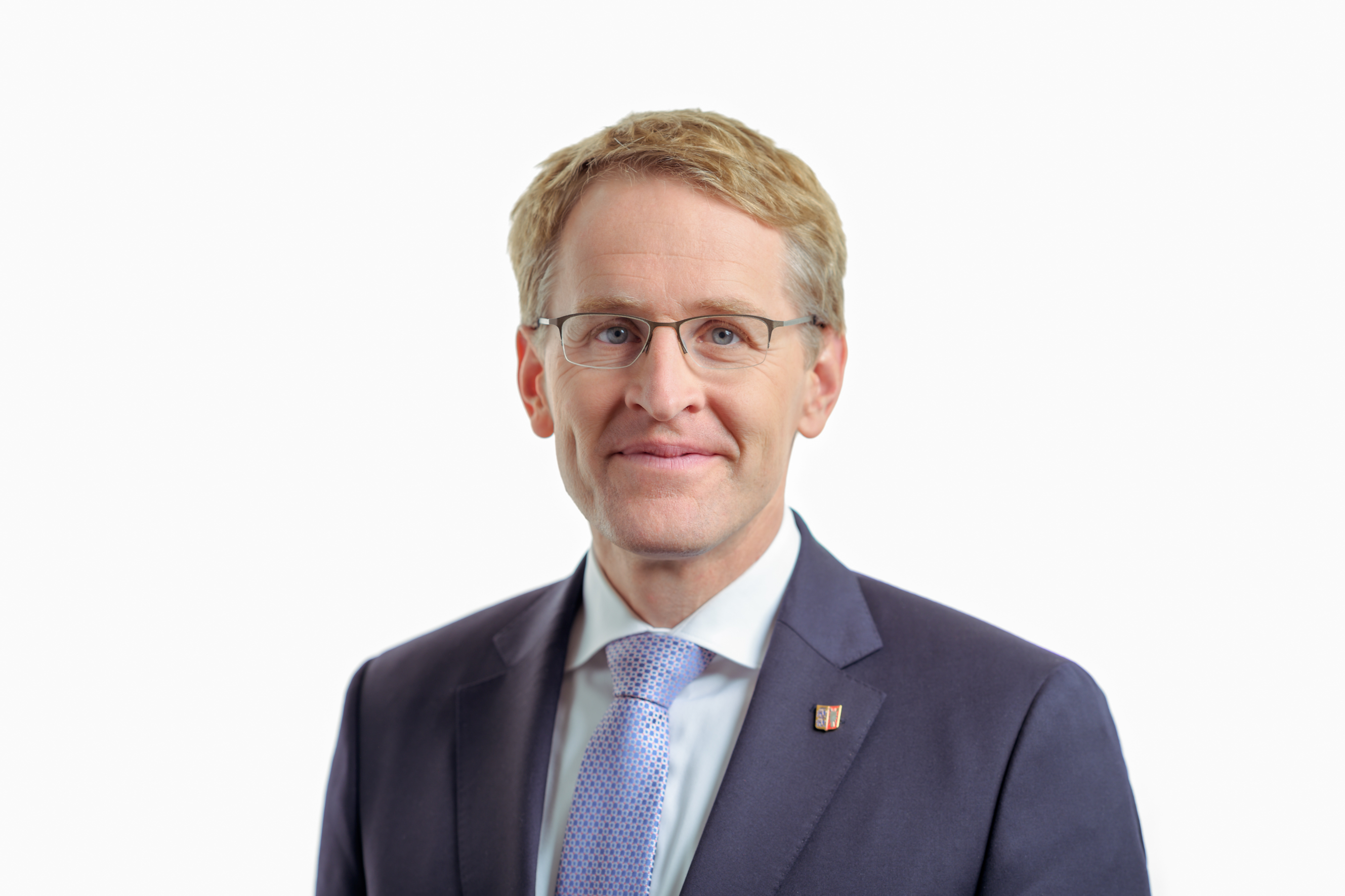 Ministerpräsident lächelt in die Kamera. er trägt einen Anzug und eine hellblaue Krawatte